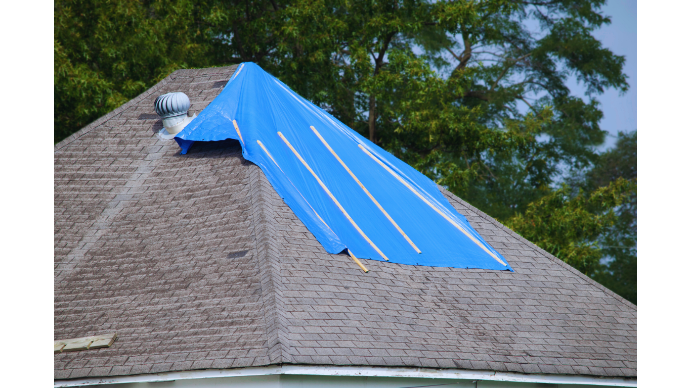 Residential roof covered with a blue tarp after hail damage, showing emergency protection while awaiting hail damage insurance claim assessment and repair.
