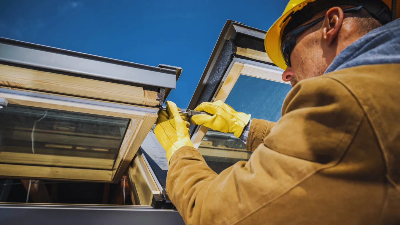 Roof inspector in safety gear examining skylight installation during a detailed roof inspection for energy efficiency and leak prevention.