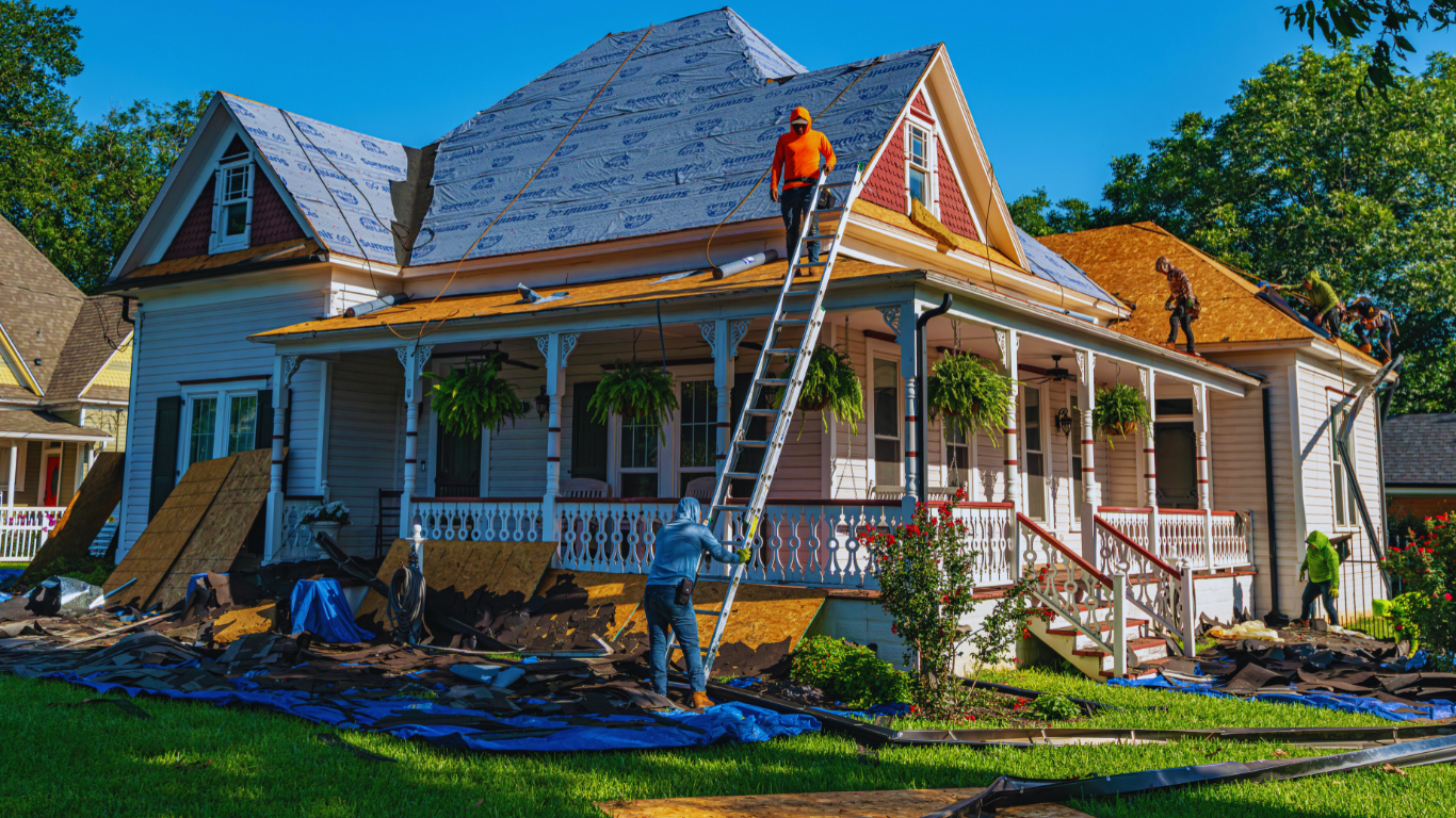 Roofing contractors performing inspection and replacement on a steep residential roof, ensuring safety, durability, and compliance with professional standards.