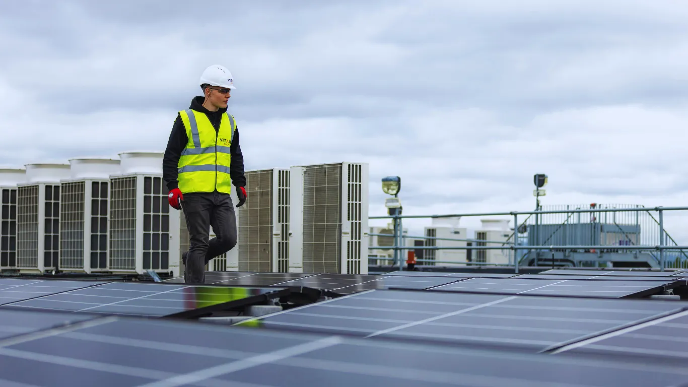Technician performing commercial roof inspection on a rooftop with solar panels and HVAC units, ensuring safety, efficiency, and compliance.