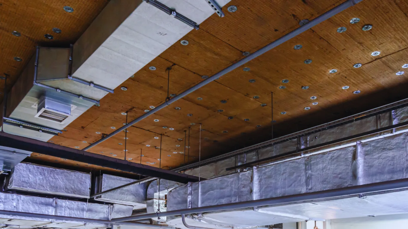 Commercial roof inspection showing interior insulation and HVAC ductwork installation to improve energy efficiency.