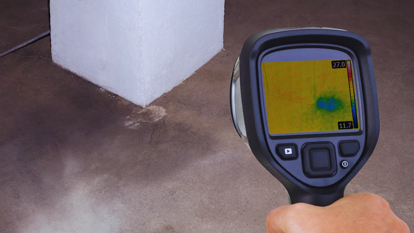 Inspector using infrared thermal imaging camera to detect hidden water damage and leaks during a professional building and roof inspection.