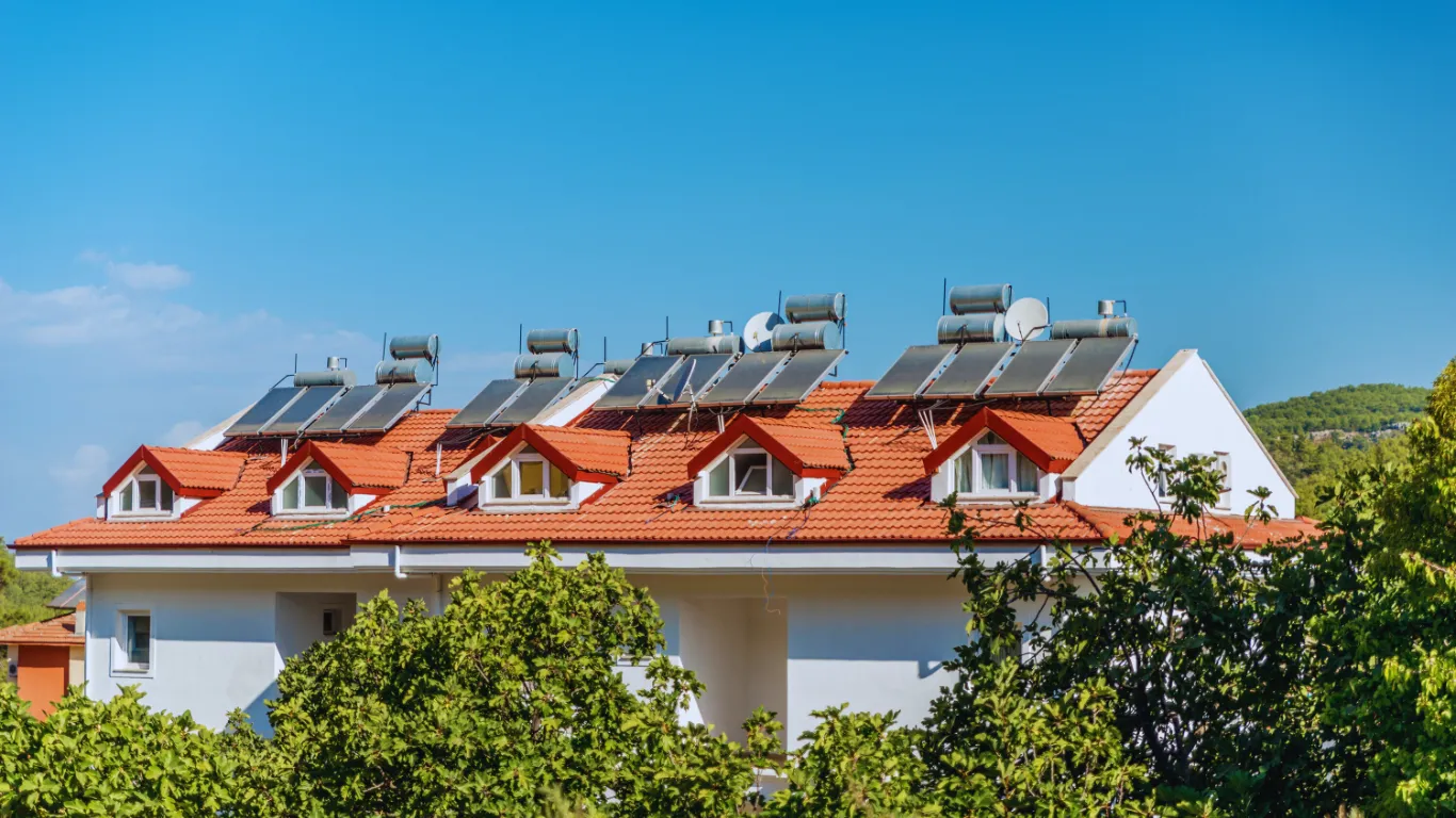 Red tile roof with solar water heating panels inspected for energy efficiency, durability, and long-term performance in a commercial building.