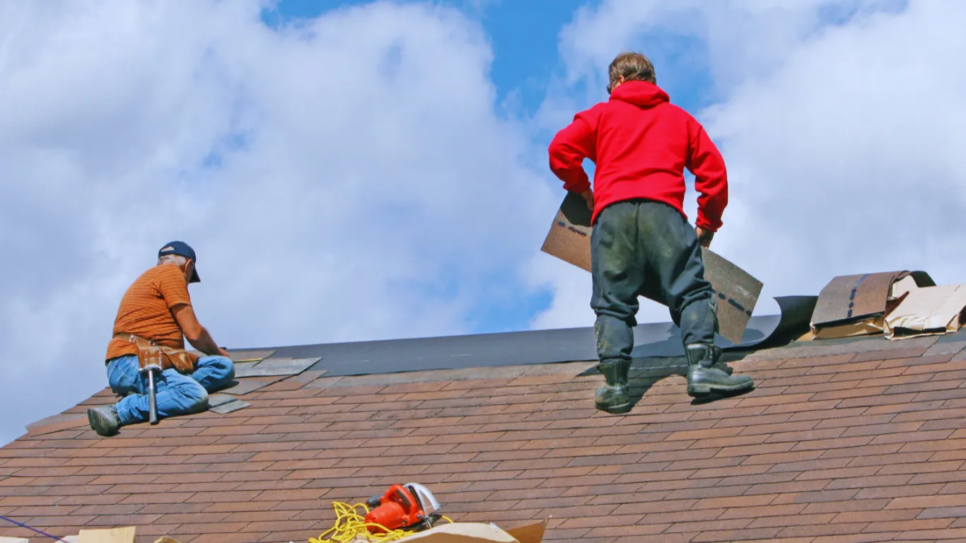 Roofing contractors installing new shingles during roof inspection and replacement project to ensure long-term protection and safety.